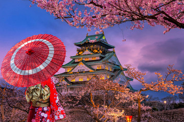 Asian women wearing kimonos See cherry blossoms in the evening around the Osaka Castle, Japan.