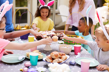 Parents With Children Wearing Bunny Ears Enjoying Outdoor Easter Party In Garden At Home