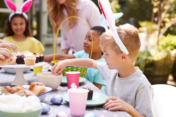 Mother With Children Wearing Bunny Ears Enjoying Outdoor Easter Party In Garden At Home