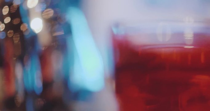 Slow motion pan across glasses with different colors spirits on the bar in night club