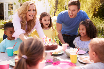 Parents And Daughter Celebrating Birthday With Friends Having Party In Garden At Home