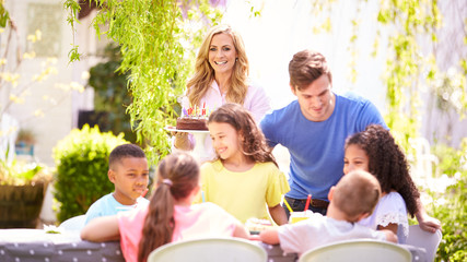 Parents And Daughter Celebrating Birthday With Friends Having Party In Garden At Home