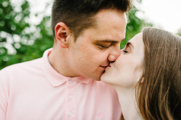 Fototapeta premium Beautiful young girl and her husband are kiss with their eyes closed against the backdrop of nature. Close up. headshot