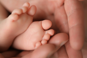 Heels of a newborn baby in the hands of a man - 316762696