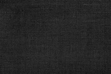Close-up texture of natural weave cloth in dark and black color. Fabric texture of natural cotton or linen textile material. Black fabric background.