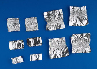 various crumpled foil used candy wrappers on a blue background