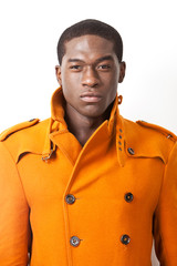 Portrait of confident young man in orange trench coat against white background