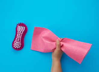 hand holds pink viscose rag for housework, blue background
