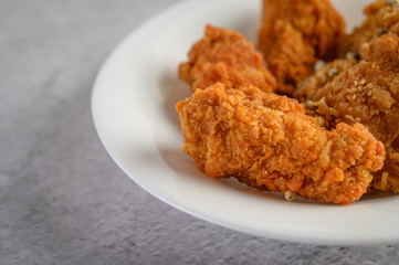 Crispy fried chicken sprinkled with pepper seeds on a white plate, Selective focus.