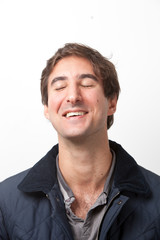 Close-up of young man with eyes closed smiling against white background