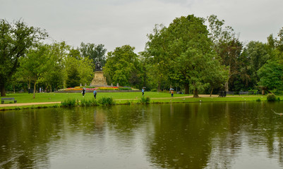 Amsterdam, Holland, August 2019. The Vondelpark: the large park in the heart of the city. On a rainy day, view of one of the lakes: people stroll with an umbrella enjoying the beauty of the place.