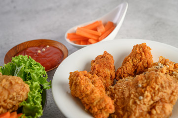 Crispy fried chicken on a white plate with tomato sauce and carrot,