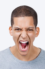 Portrait of aggressive young mixed race man screaming against white background