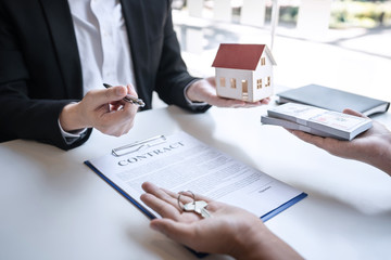 Sale purchase contract to buy a house, Real estate agent are presenting home loan and giving keys to customer after signing contract to buy house with approved property application form