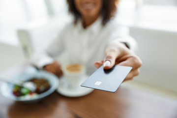 Portrait of african american woman paying in cafe with credit card