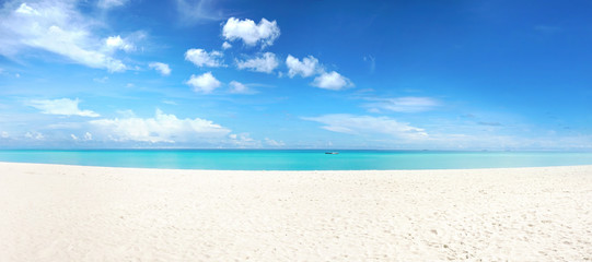 Beautiful beach with white sand, turquoise ocean and blue sky with clouds in sunny day. Panoramic view. Natural background for summer vacation.