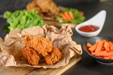 Crispy fried chicken on a cutting board with tomato sauce and carrot, Selective focus.