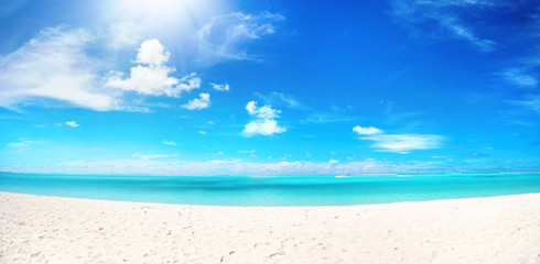 Fototapeta na wymiar Beautiful beach with white sand, turquoise ocean water and blue sky with clouds in sunny day. Panoramic view. Natural background for summer vacation.