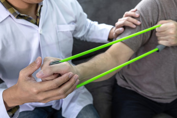 Doctor physiotherapist treating arm pain patient doing physical therapy exercises with his therapist in clinic - sport physical therapy concept