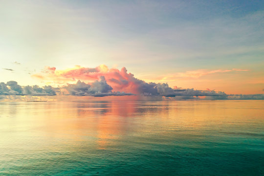 Beautiful cloud over ocean water at sunset in Golden pink blue and green tones. Colorful natural landscape, copy space.