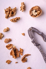 Walnuts heap food with half peeled nut, cracked nutshell, near to vintage nutcracker on white background, top view, healthy food concept