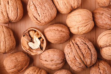 Walnuts heap food in wooden bowl with half peeled nut, top view, healthy food concept