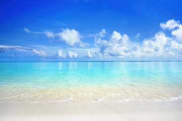 Beautiful sandy beach with white sand and rolling calm wave of turquoise ocean on Sunny day. White...