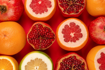 Grapefruit, orange, pomegranate, citrus sweetie on red background.