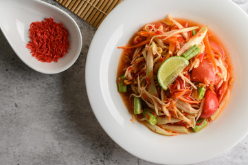 Thai papaya salad in a white plate and dried shrimp.