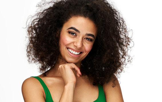 Portrait of cheerful african american woman with freckles and afro hairstyle isolated on white background