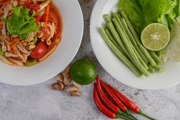Thai papaya salad in a white plate with chili, lime, and garlic.