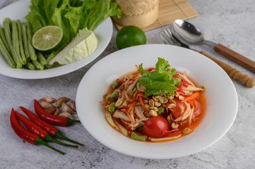 Thai papaya salad in a white plate with chili, lime, and garlic.