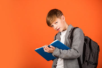 Final exam. Little child take exam brown background. Small boy write in bluebook. Written exam....