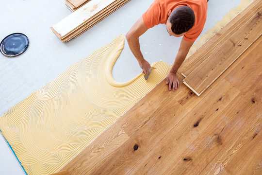 Craftsman is laying parquet flooring in a modern new building