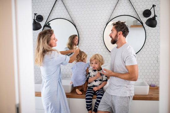 Young family with two small children indoors in bathroom, talking.