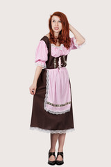 Young confused woman in maid costume standing against gray background