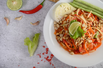 Thai papaya salad in a white plate with chili, lime, and garlic.