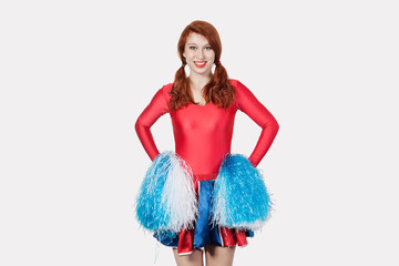 Portrait of young woman in cheer leader costume standing against gray background