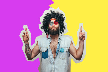 Friendly bearded young male hippie with curly hair in stylish sunglasses isolated on colorful background