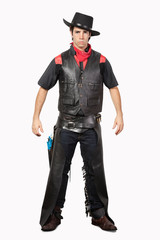 Portrait of young cowboy in black leather vest standing against gray background