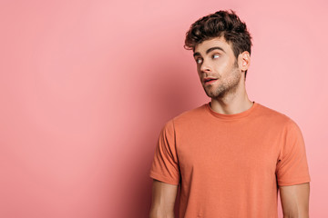 Fototapeta premium handsome, dreamy man looking away on pink background