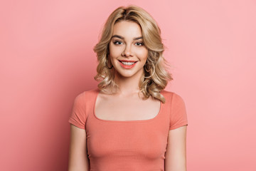 attractive, happy girl smiling at camera on pink background