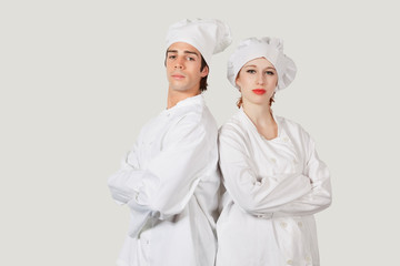Portrait of two confident chefs with arms crossed against gray background