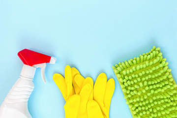 Detergents, cleaning accessories, rubber glove and rags for dishwashing on a blue background. Cleaning service concept. Top view, flat lay. Copy space.