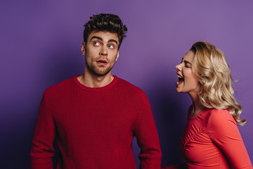irritated girl screaming at boyfriend looking away on purple background