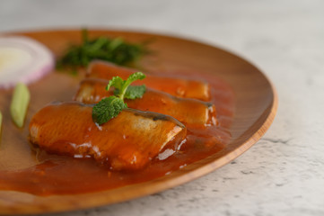 Spicy salad of sardine in tomato sauce on wooden tray