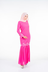 Beautiful female model wearing pink modern kurung, a modern urban lifestyle apparel for Muslim women isolated on white background. Beauty and hijab fashion concept.