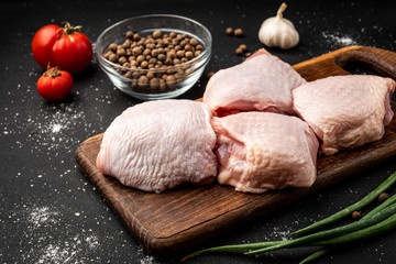 Raw chicken thigh on black background. © Natallia