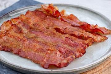 Crispy fried bacon in a cast iron pan on a gray background.