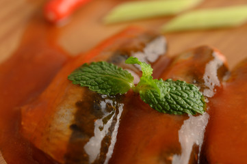 Appetizing salad of sardine in tomato sauce on wooden tray